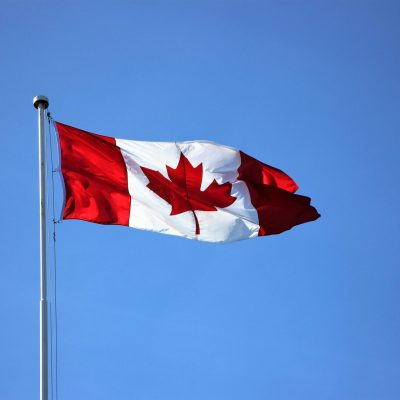 Canadian flag waving proudly against a clear blue sky in Victoria, BC.